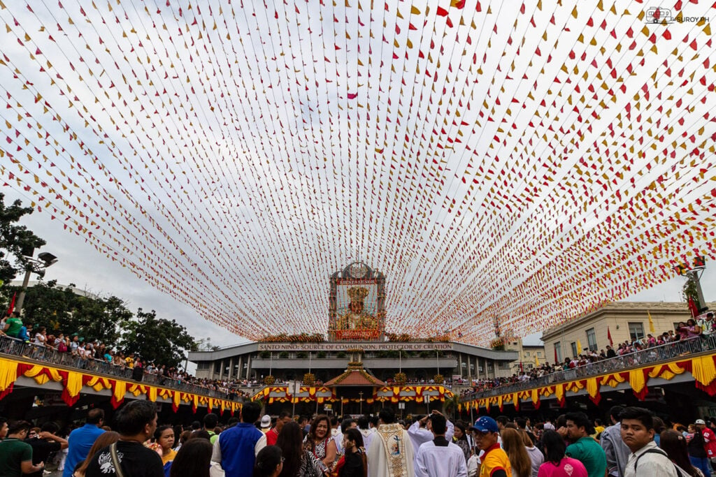 Devotees gather under a canopy of vibrant flags during Sinulog Festival at the Basilica Minore de Sto. Niño, celebrating faith and tradition in the heart of Cebu.