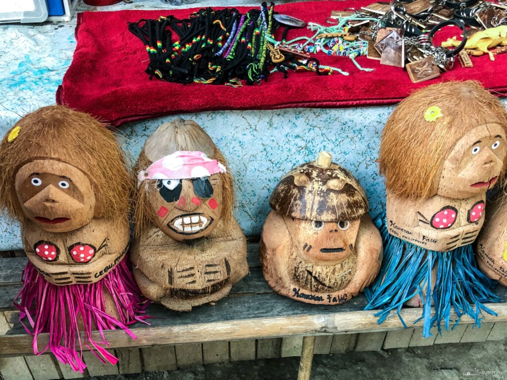 Painted coconut shell souvenirs lined up on a stall near the Kawasan Falls entrance