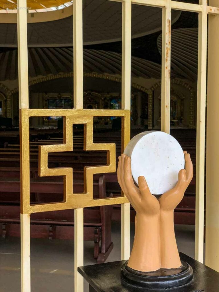 Two hands hold the Body of Christ outside the chapel.