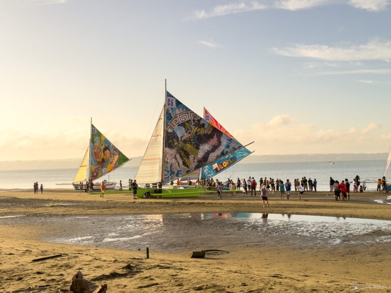 Colorful paraws with large painted sails stationed on Villa Beach as people admire them during the Paraw Regatta Festival in Iloilo.