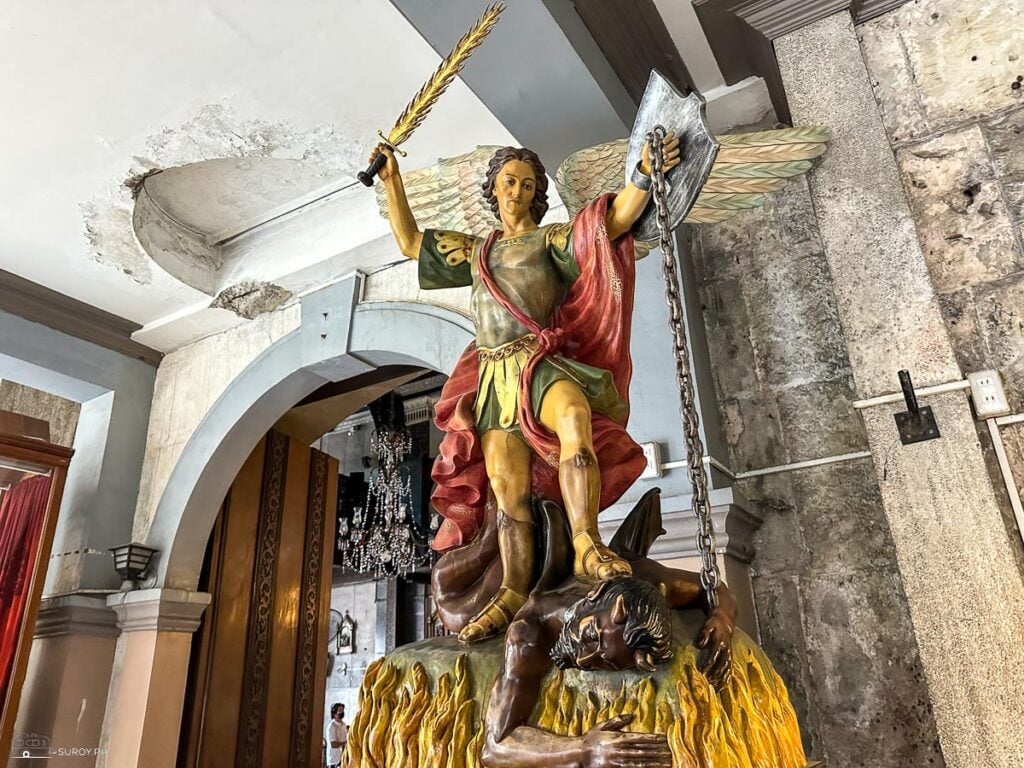 A striking statue of Saint Michael the Archangel triumphing over evil, a symbol of protection and faith within the walls of the church.
