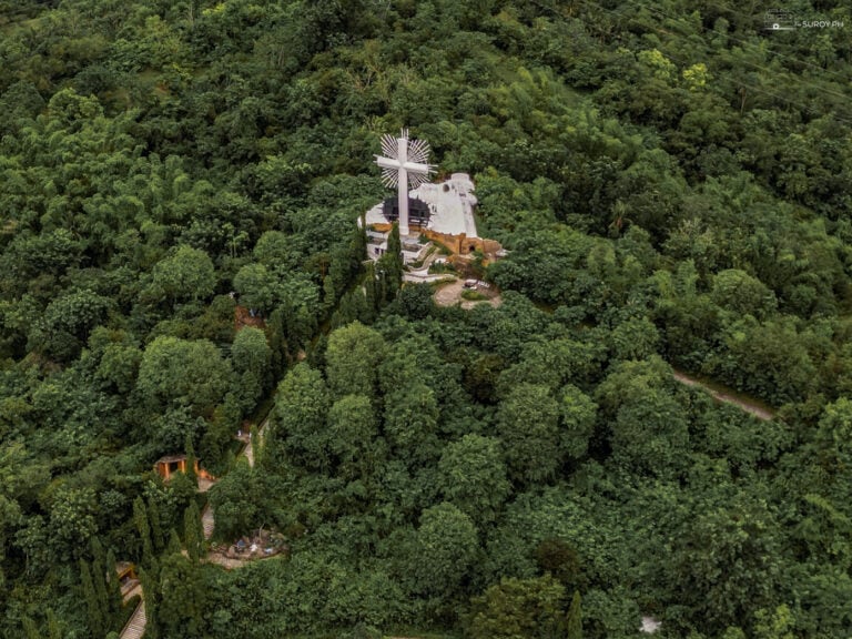 An aerial view of the towering cross on Pilgrimage Hill in Garin Farm Pilgrimage Resort in Iloilo, offering a spiritual journey and stunning vistas.