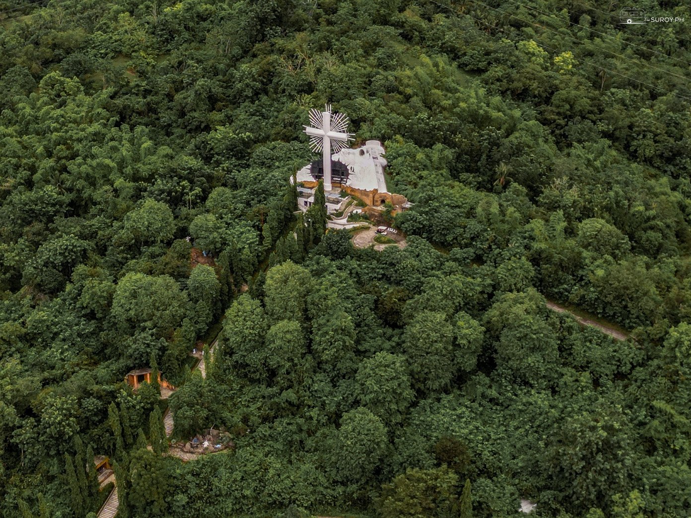An aerial view of the towering cross on Pilgrimage Hill in Garin Farm Pilgrimage Resort in Iloilo, offering a spiritual journey and stunning vistas.