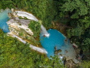 Drone shot of Inambakan Falls in Ginatilan, Cebu, featuring a turquoise pool and two separate streams of cascading water formed after Typhoon Kristine.