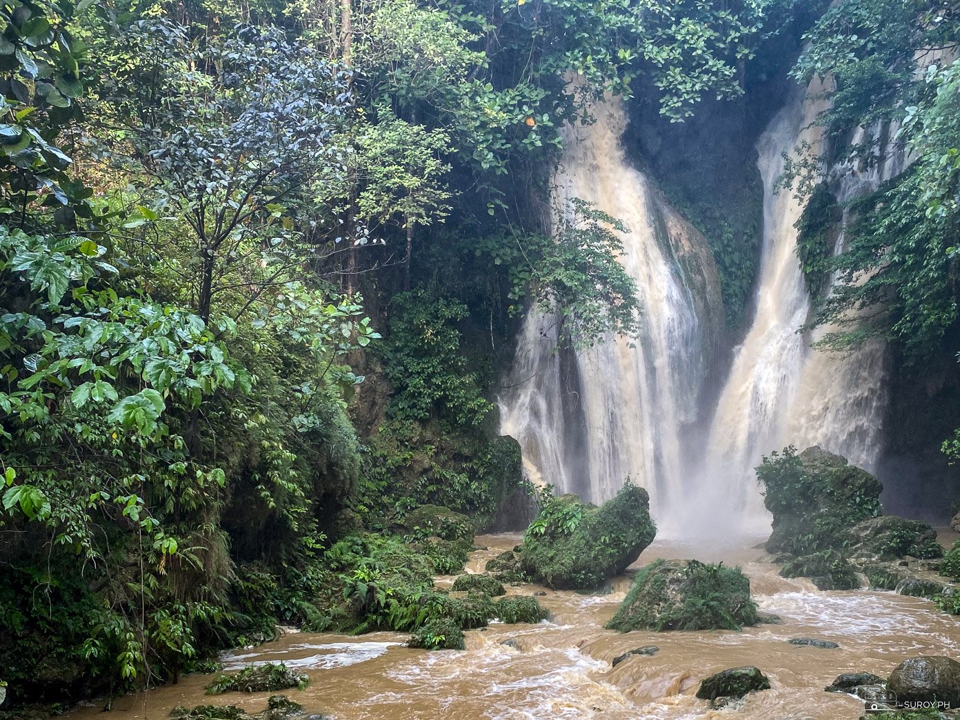 A picturesque view of the cascading waters at Mag-Aso Falls in Kabankalan, surrounded by verdant foliage.