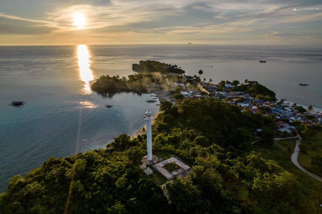 The lighthouse on Malapascua Island stands tall as the sun sets in the distance.