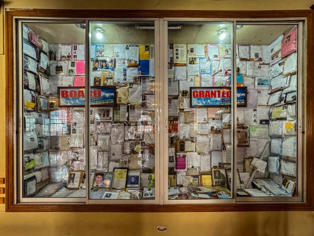 A display case filled with letters of gratitude and photographs of answered prayers, showcasing the deep faith and devotion of the pilgrims visiting Simala Church.