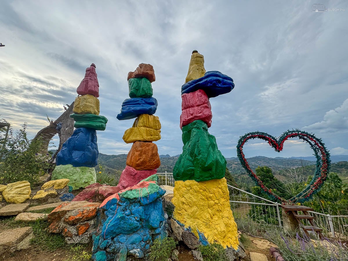 Painted totems and a heart frame among the flower beds at Sirao Garden.