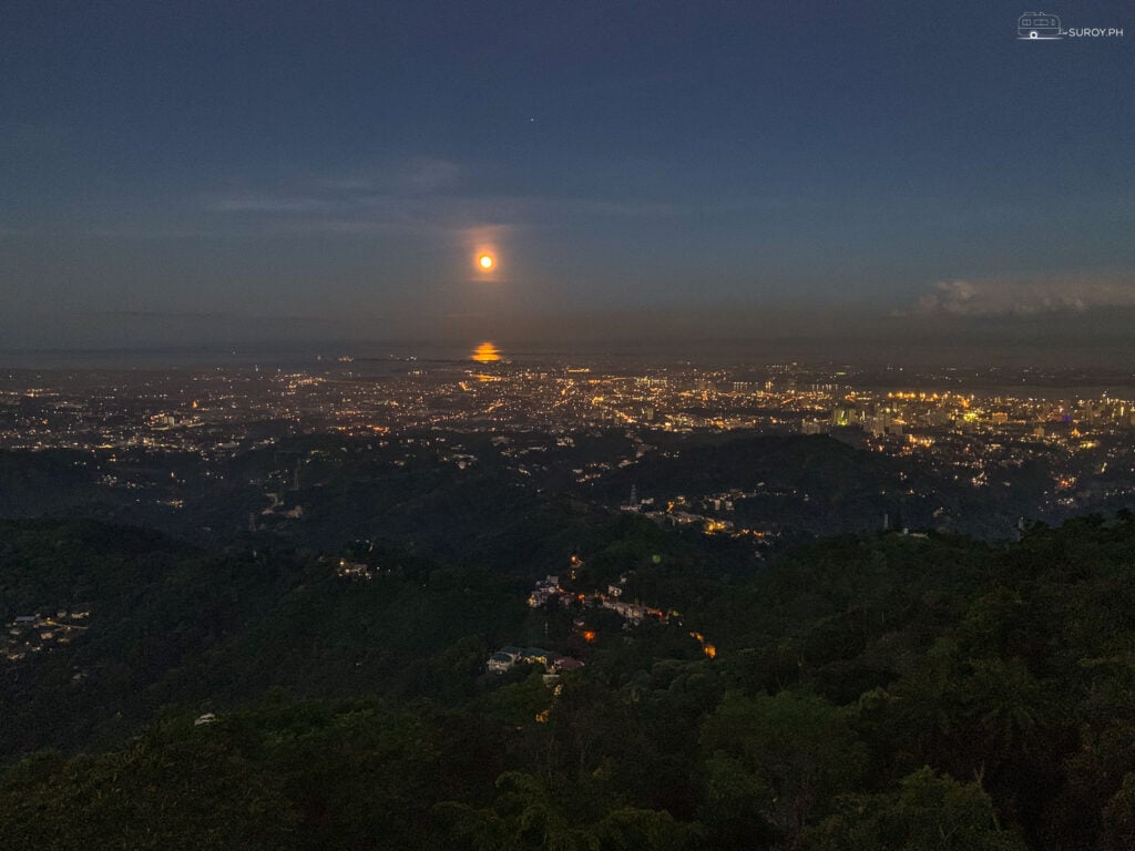 Witness the enchanting sight of the city lights under the glow of the moon. 