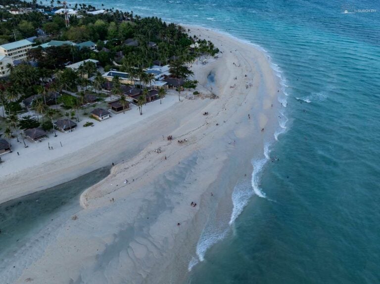 Aerial view of the Kota Beach sandbar in Santa Fe, Bantayan Island, with resort palms on the left and waves breaking along the sand spit