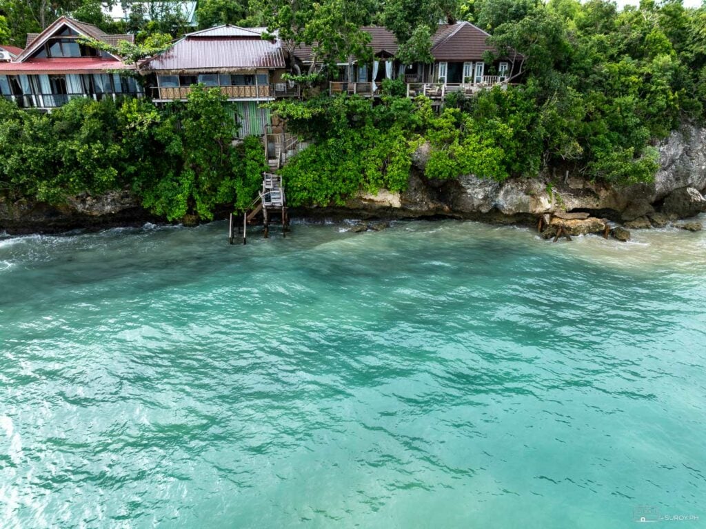 A closer look at the charming ocean view cottages, nestled among lush greenery and overlooking the tranquil waters.