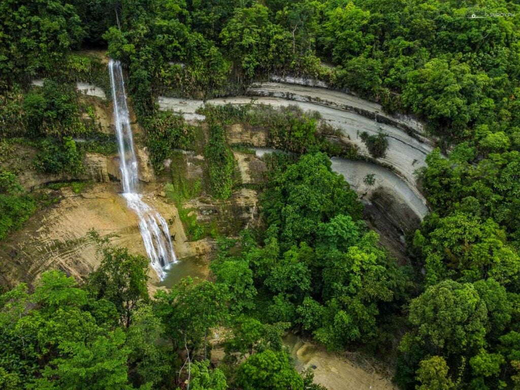 Cascading Elegance: The stunning three-tiered Can-Umantad Falls in Candijay, Bohol, cascading down into the crystal-clear pool below, set against a backdrop of verdant foliage.