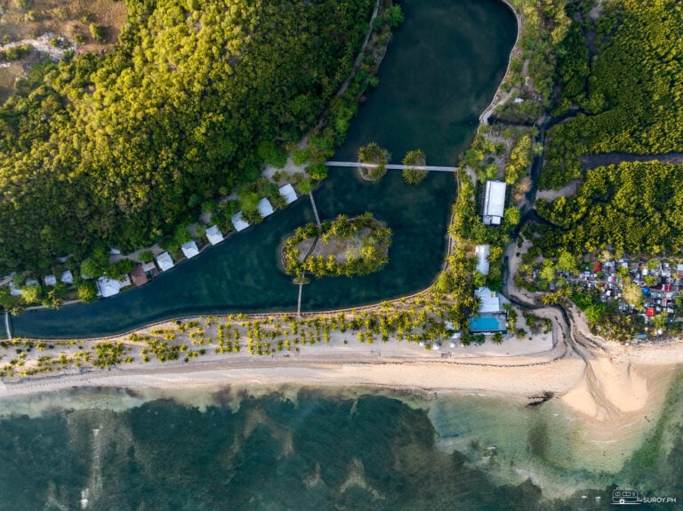 A stunning aerial view of Golden Sands Destination Resort in Daanbantayan, highlighting its beautiful beach, lush palm trees, and serene lagoon.