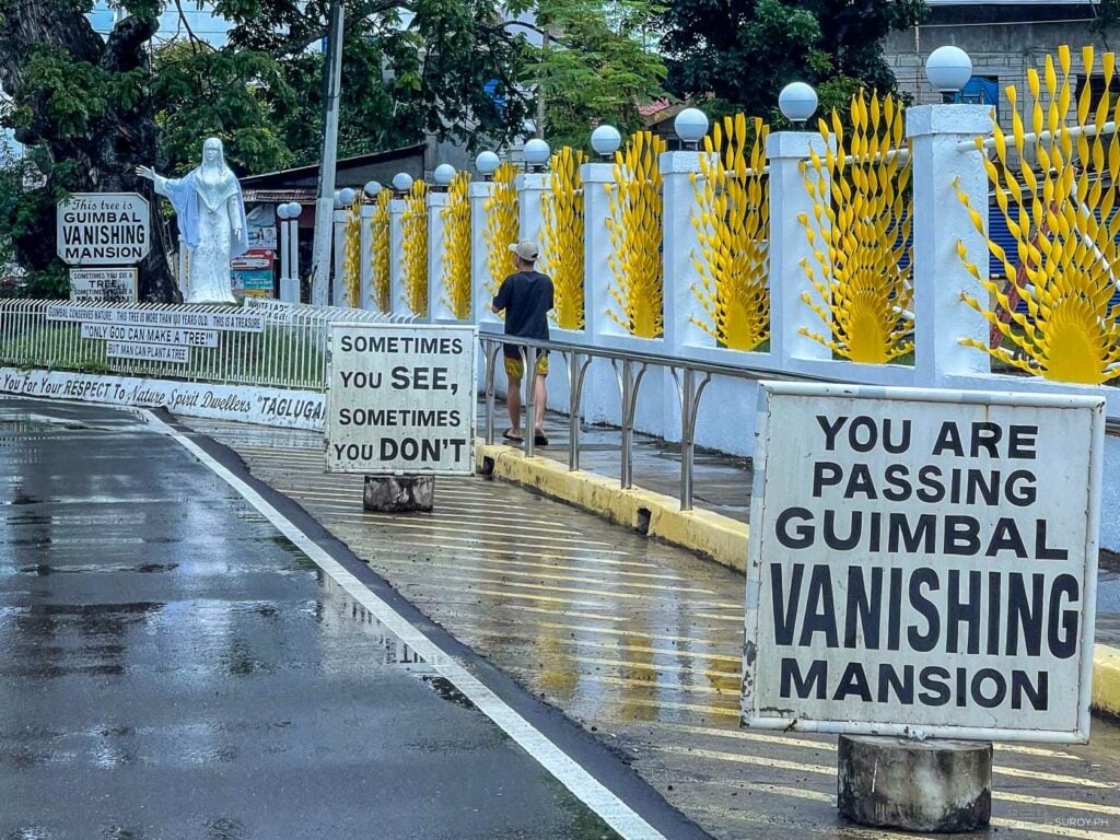 The entrance to the enigmatic Guimbal Vanishing Mansion, where signs remind you of its mysterious nature.