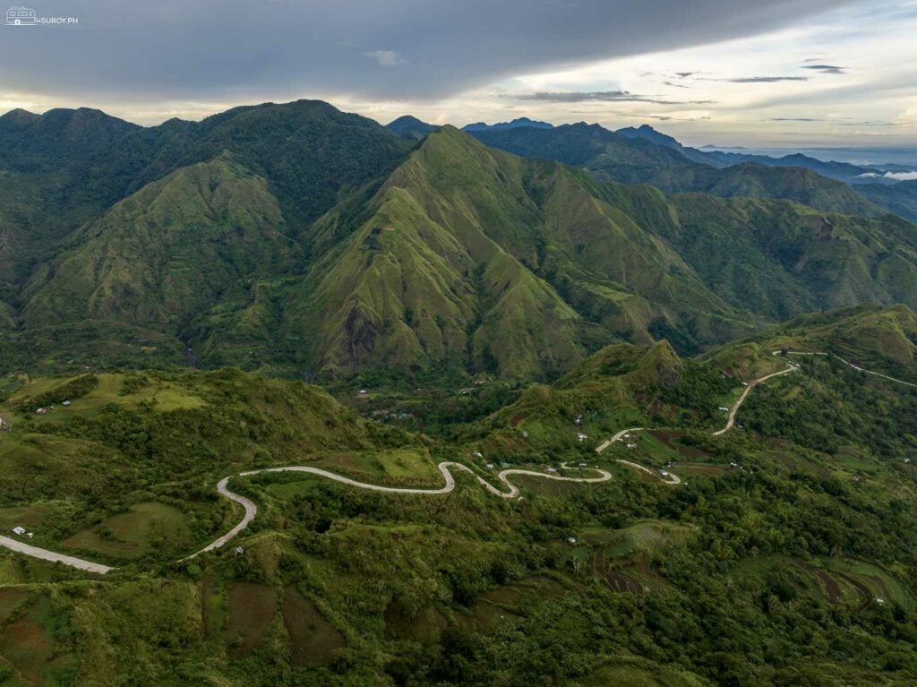 A panoramic view of the verdant valleys and rolling hills from the Igtuble Tubungan View Deck, with Mt. Tambara Peak in the background.