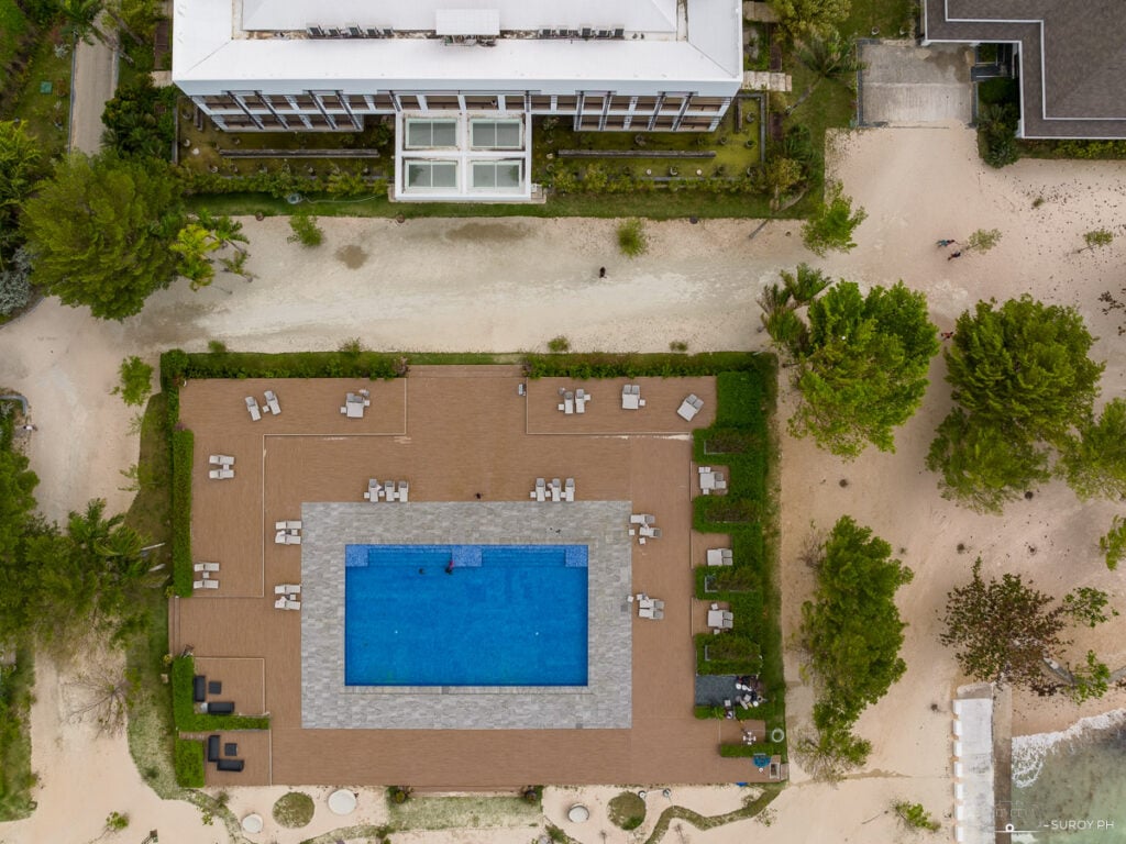 An aerial view of Kandaya Resort’s inviting pool, a centerpiece of relaxation surrounded by lounge areas and greenery, offering the ultimate escape from daily stress.