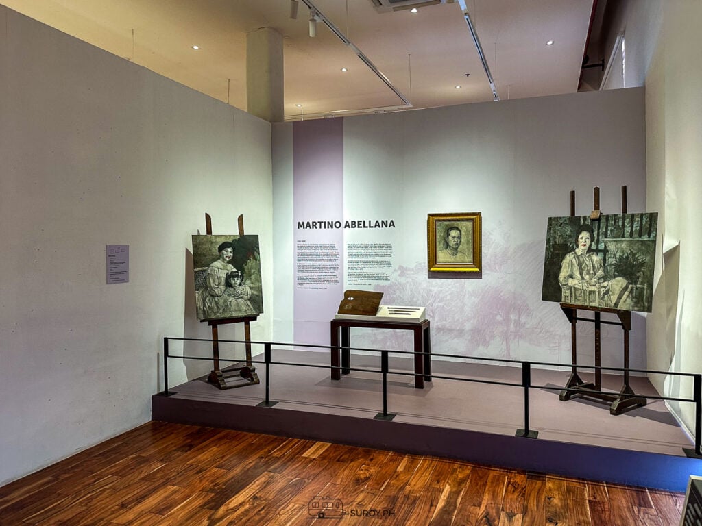 A gallery wall for Martino Abellana with two paintings on easels and a framed portrait
