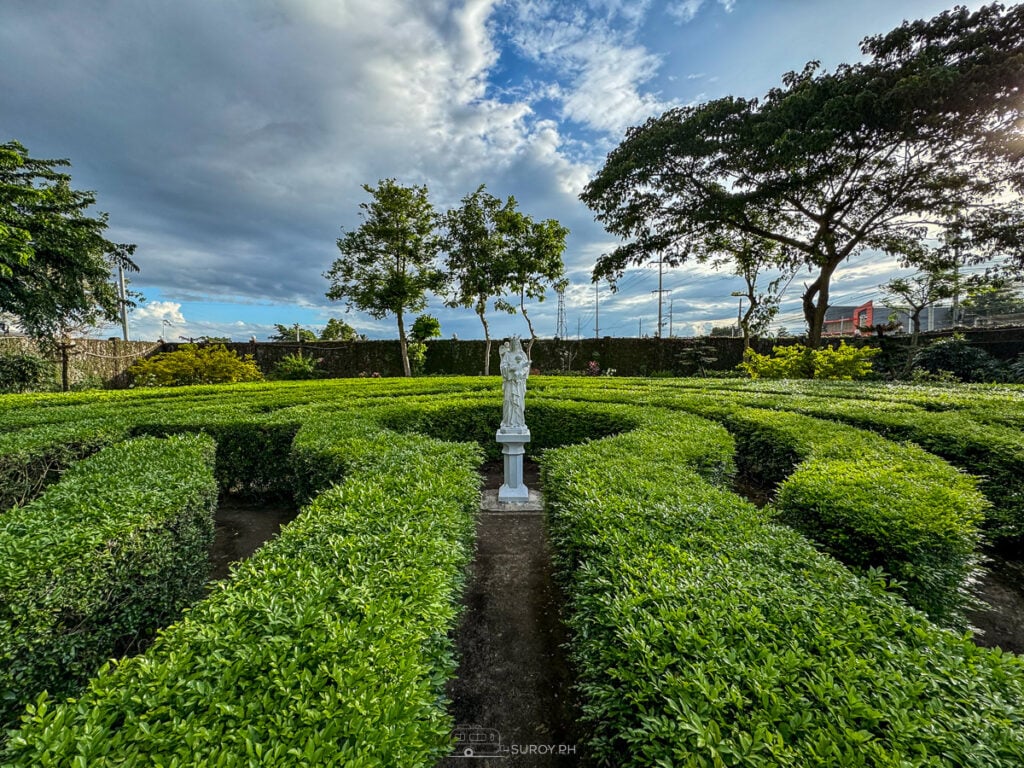 A stunning close-up of the angel statue in the labyrinth garden, where detailed wings and flowing robes symbolize protection and serenity.
