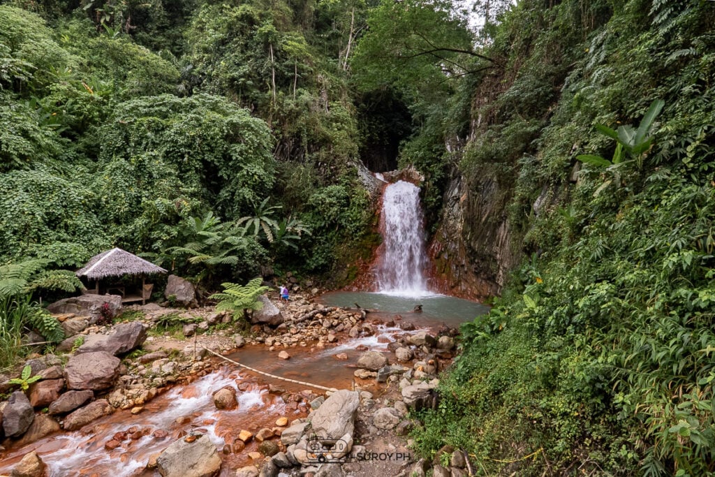 Pulang Bato Falls cascades down its signature red rocks, creating a breathtaking contrast against the lush green backdrop of Valencia, Negros Oriental.