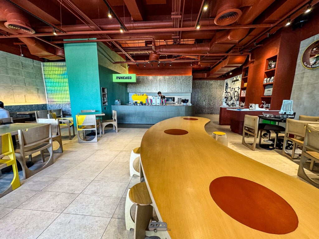 Wide shot of Punched Coffee’s interior featuring curved tables, bright walls, and modern design.
