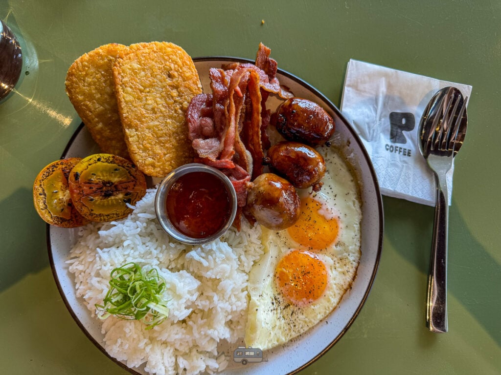A plate of big breakfast with hashbrowns, bacon, eggs, Cebu chorizo, and rice.