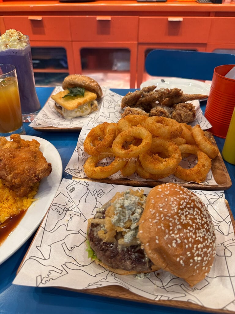Burgers, onion rings, chick poppers and drinks spread across a blue table at 8Cuts SM City Cebu