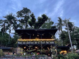 The timber hall of Acacia Steakhouse Cebu lit from within at dusk beneath tall trees