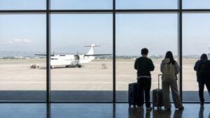 Unbranded turboprop aircraft at Clark airport with travelers viewing the apron through a terminal window