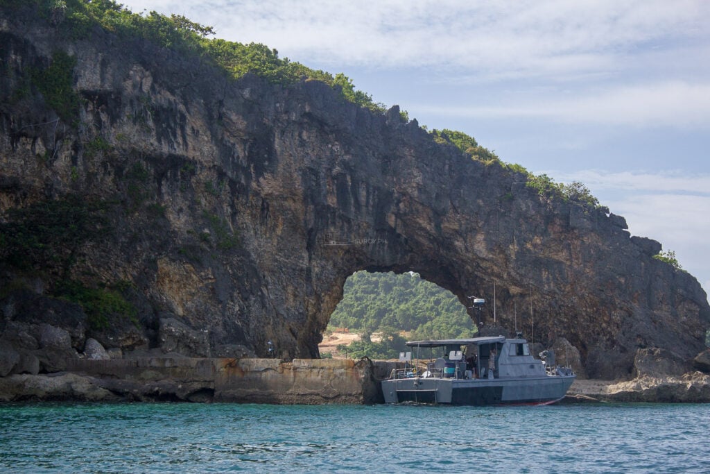 Tour boat beside a natural rock arch near Boracay Island