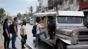 Commuters boarding a traditional jeepney on a wet Cebu City street