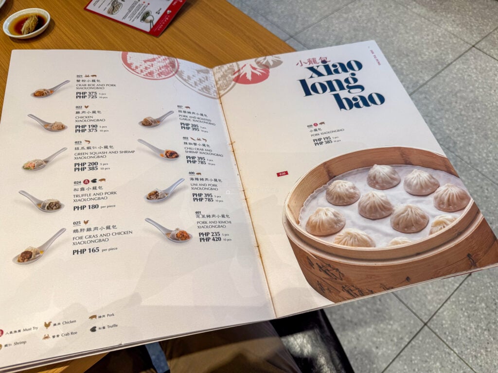 The open Din Tai Fung menu at the xiaolongbao pages, showing ten varieties with prices in pesos for five and ten pieces