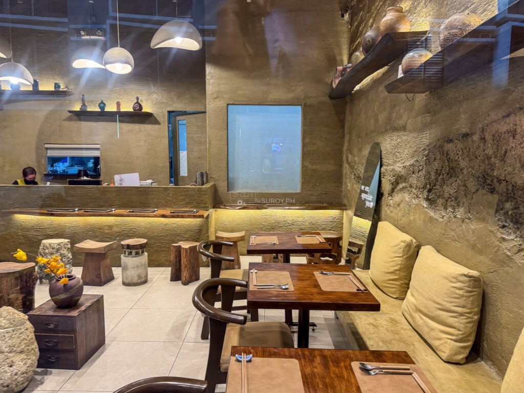 The rough stone wall, timber tables and low banquette seating inside Hosaku Japanese restaurant at Banilad High Street Cebu