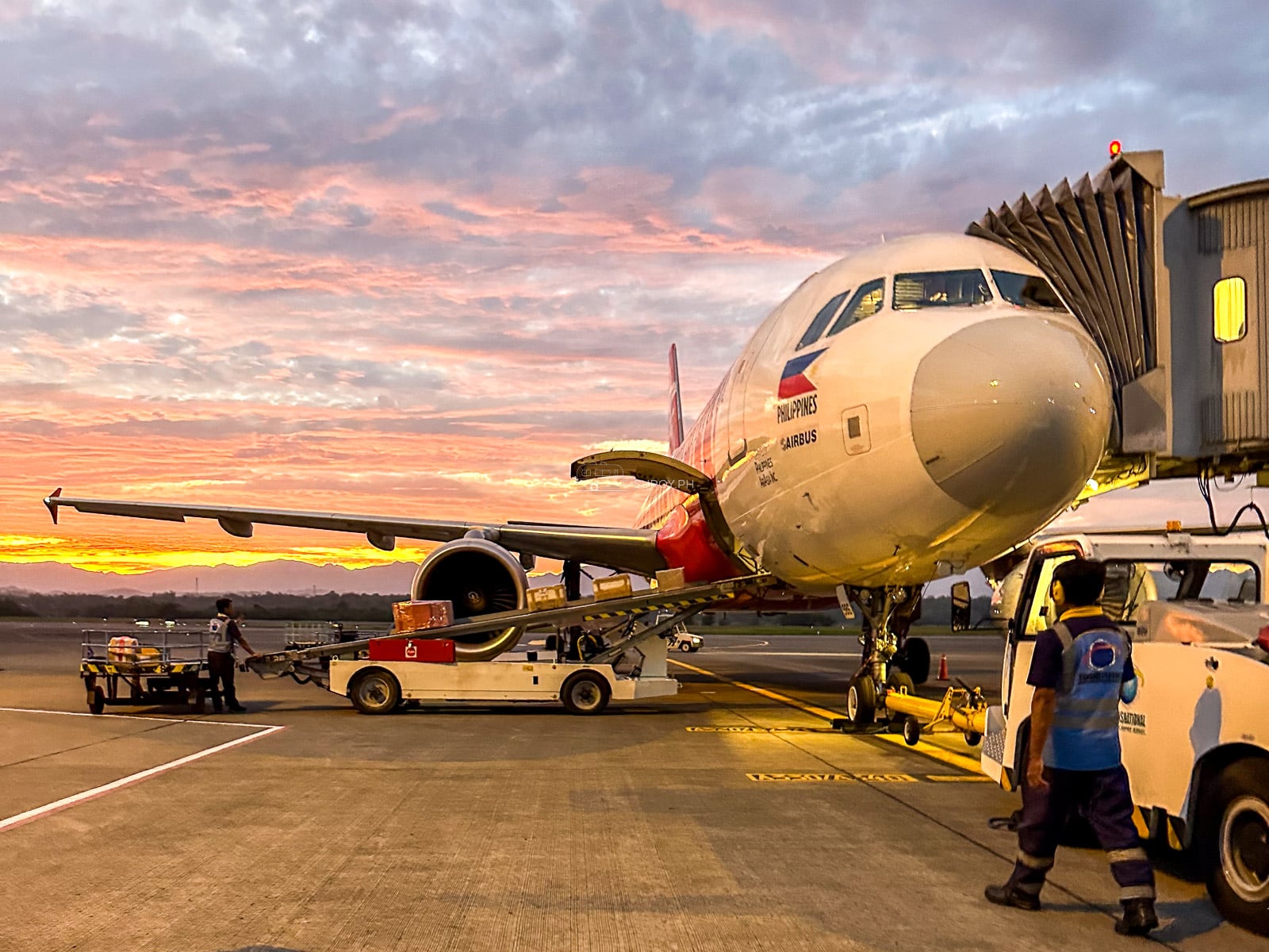 AirAsia aircraft parked at an Iloilo Airport jet bridge during sunset