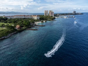 Aerial view of the turquoise reef flat and deep blue drop-off along the Punta Engano coast in Lapu-Lapu City with a jetski wake crossing the frame