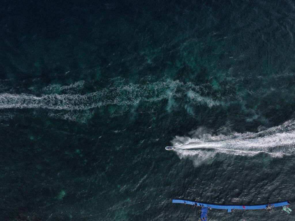 Top down aerial of a shallow coral reef flat meeting deep blue water with a floating pontoon