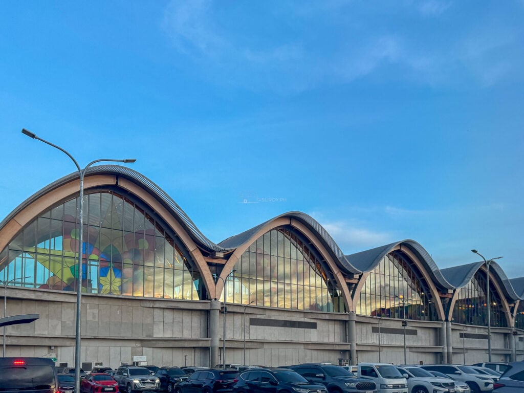 Curved Terminal 2 roof and stained glass facade at blue hour