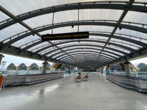 Covered walkway marked Terminal 2 International Departures with luggage trolleys