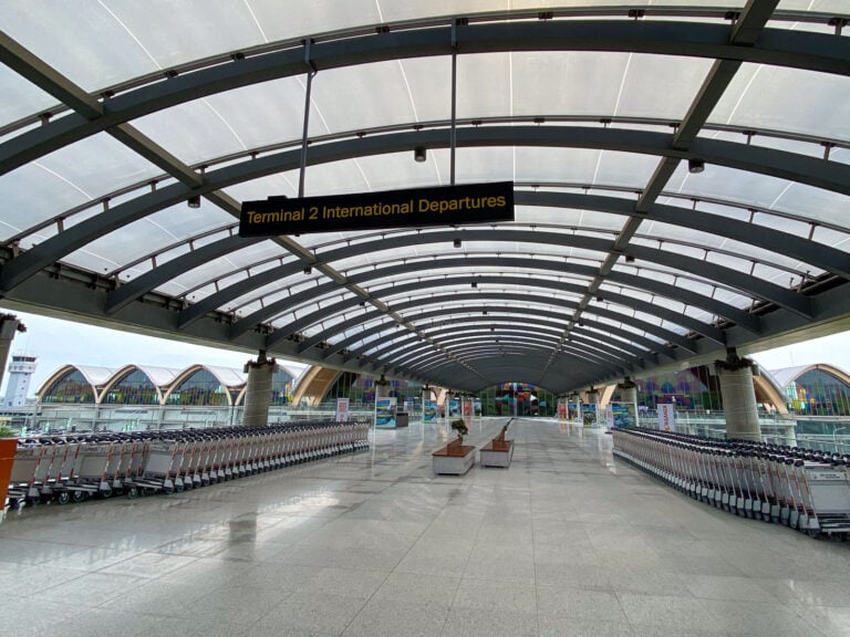 Covered walkway marked Terminal 2 International Departures with luggage trolleys