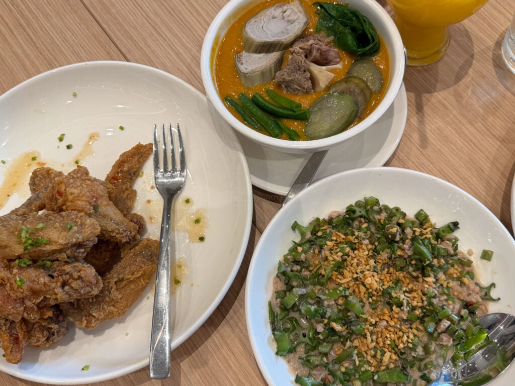 A shared table at Manam SM City Cebu with gising gising, a bowl of sinigang and fried chicken pieces