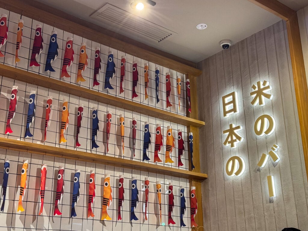 Rows of printed koinobori carp streamers on the wall at Ooma SM City Cebu beside a neon sign reading Nihon no baa