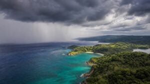 Tropical rain clouds and a rain curtain over a sunlit Philippine island coastline