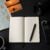 Neutral travel newsroom desk with notebook, camera lens, map, and audio recorder