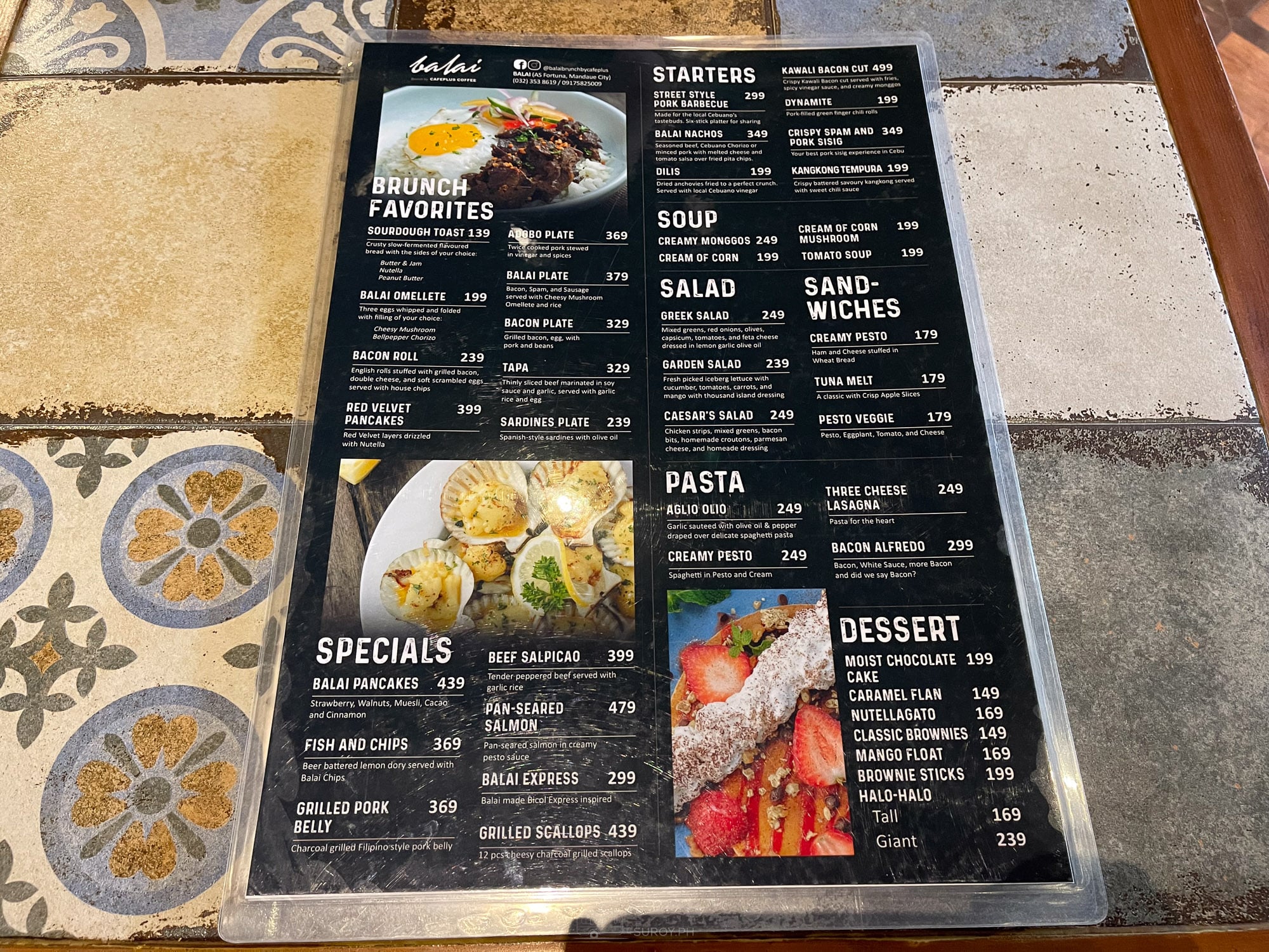 The Balai menu board on a tiled table showing brunch, starters, pasta, specials and dessert prices