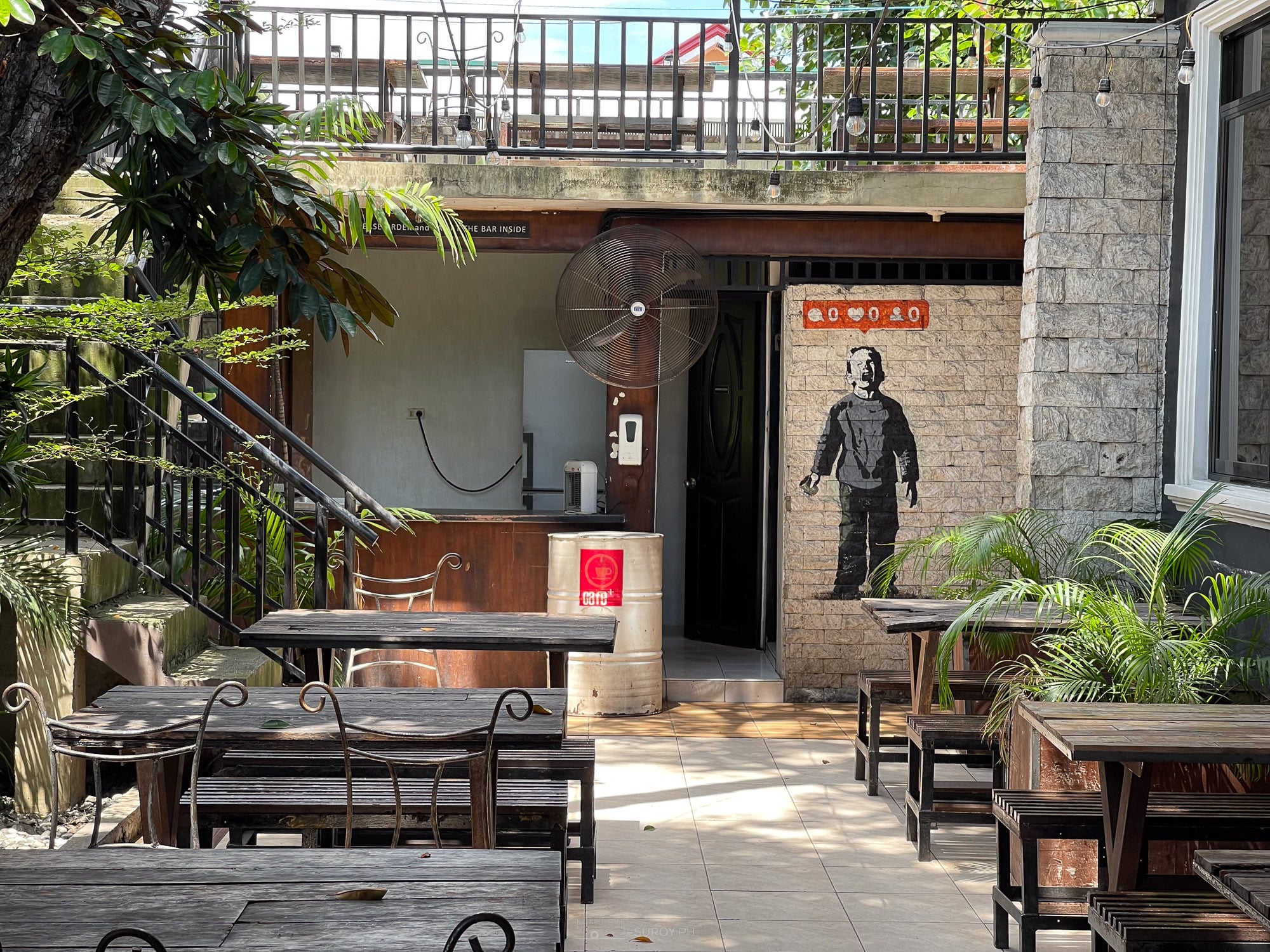 Courtyard seating at Balai on A.S. Fortuna with wooden tables, stone steps and garden planting