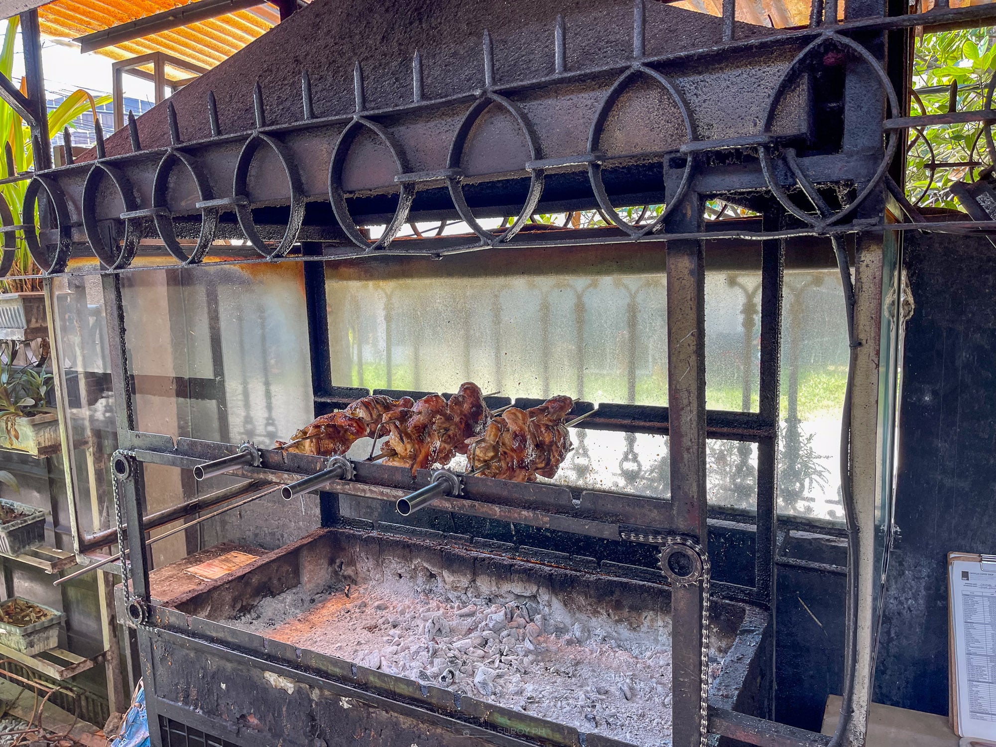 Charcoal rotisserie at Balai with whole chickens turning on a spit over coals