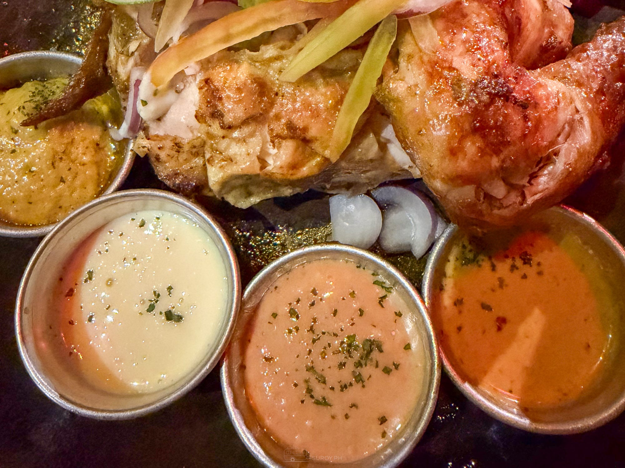 Quartered charcoal roasted Farooj chicken at Balai served with four dipping sauces in metal tins