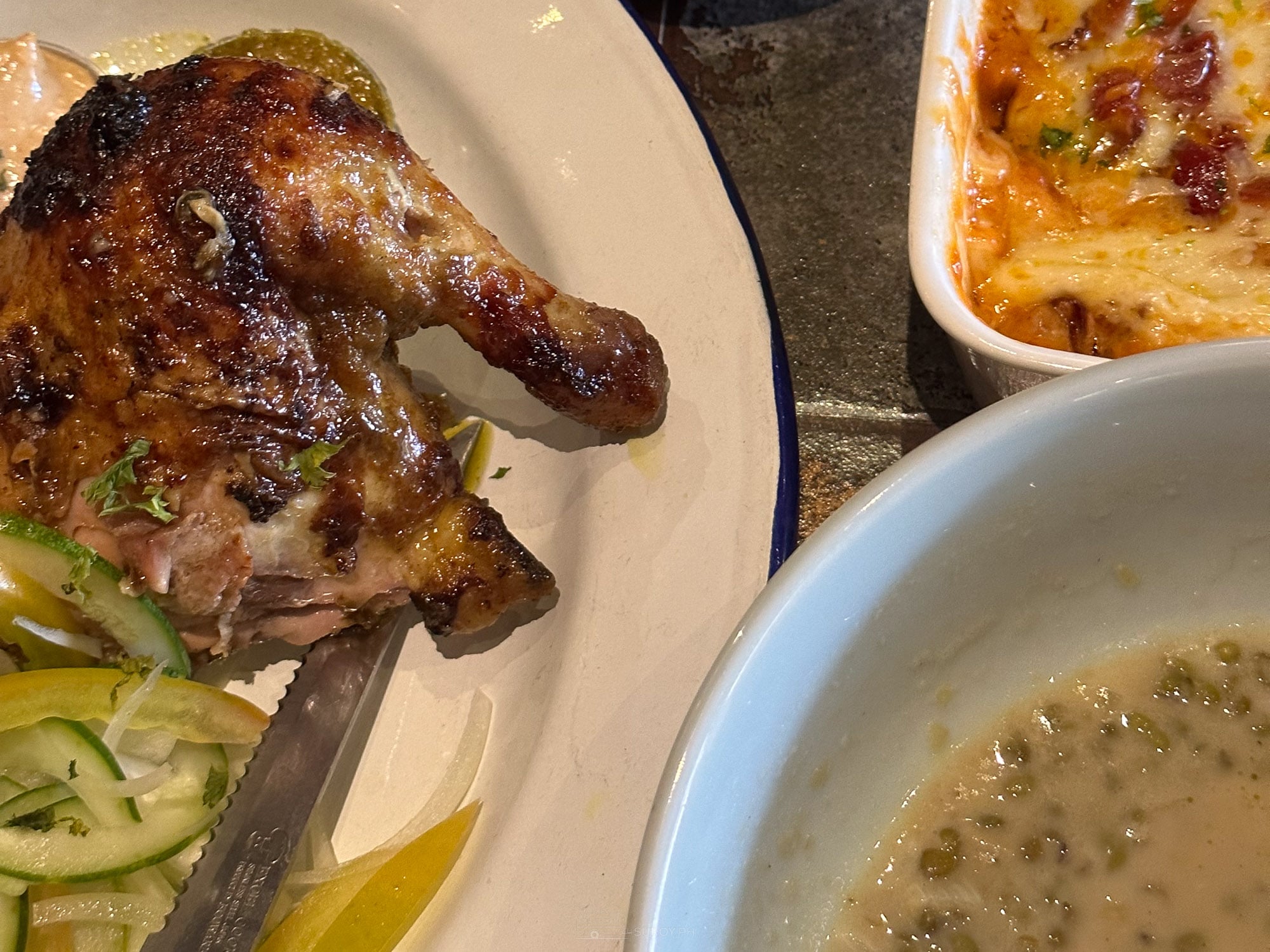 Farooj roast chicken plate at Balai with cucumber, lemon, baked pasta and a bowl of creamy monggo