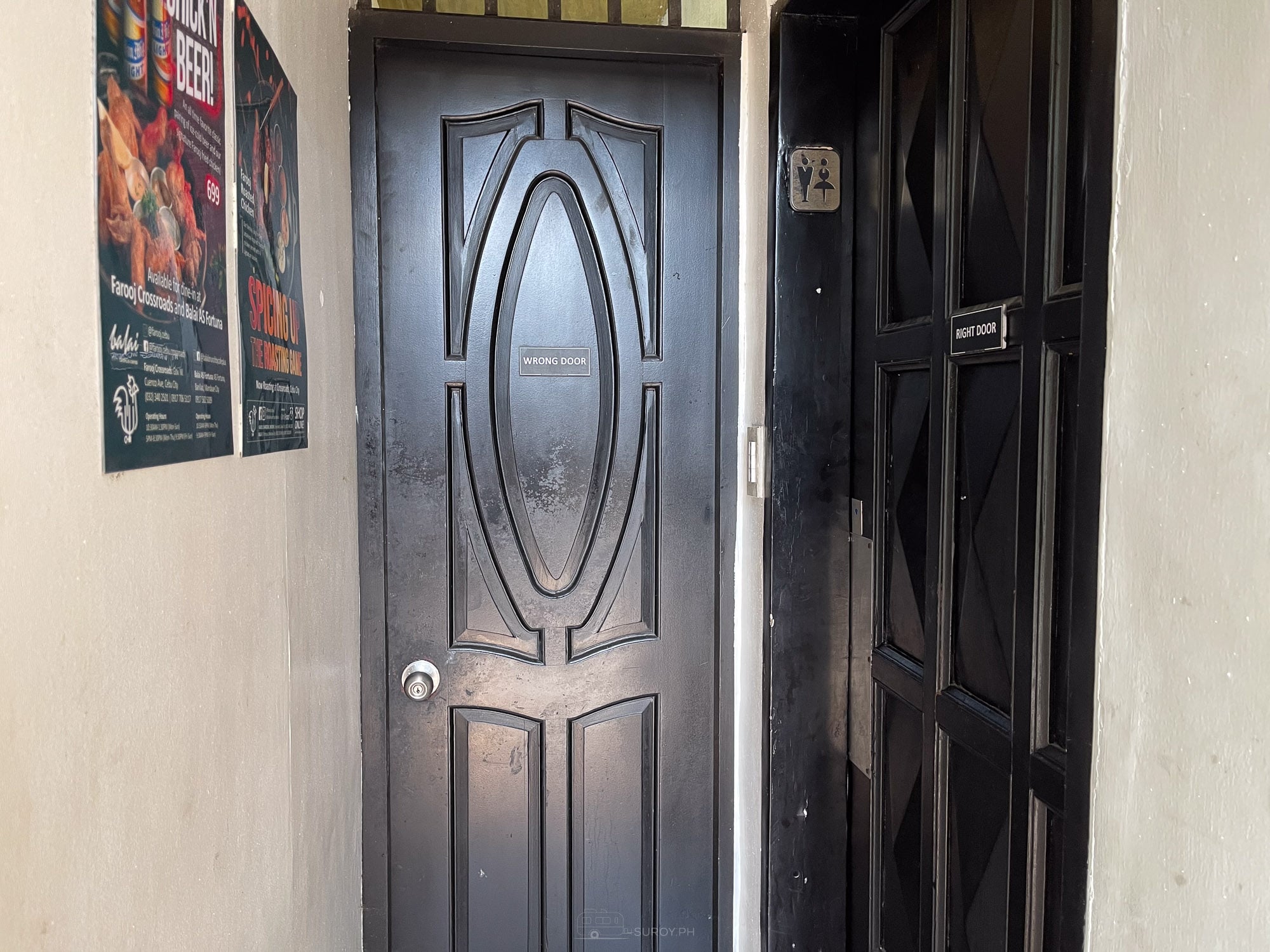 Restroom doors at Balai labeled wrong door and right door, beside posters for Farooj roasted chicken