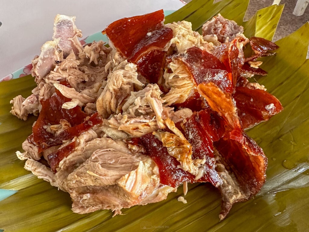 Chopped Carcar lechon piled on a banana leaf, wet with the dark drippings poured over it