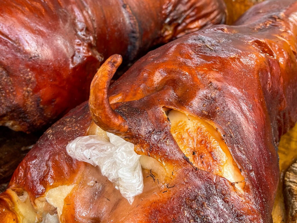 Close up of the lacquered mahogany skin and curled tail of a whole roast lechon in Carcar